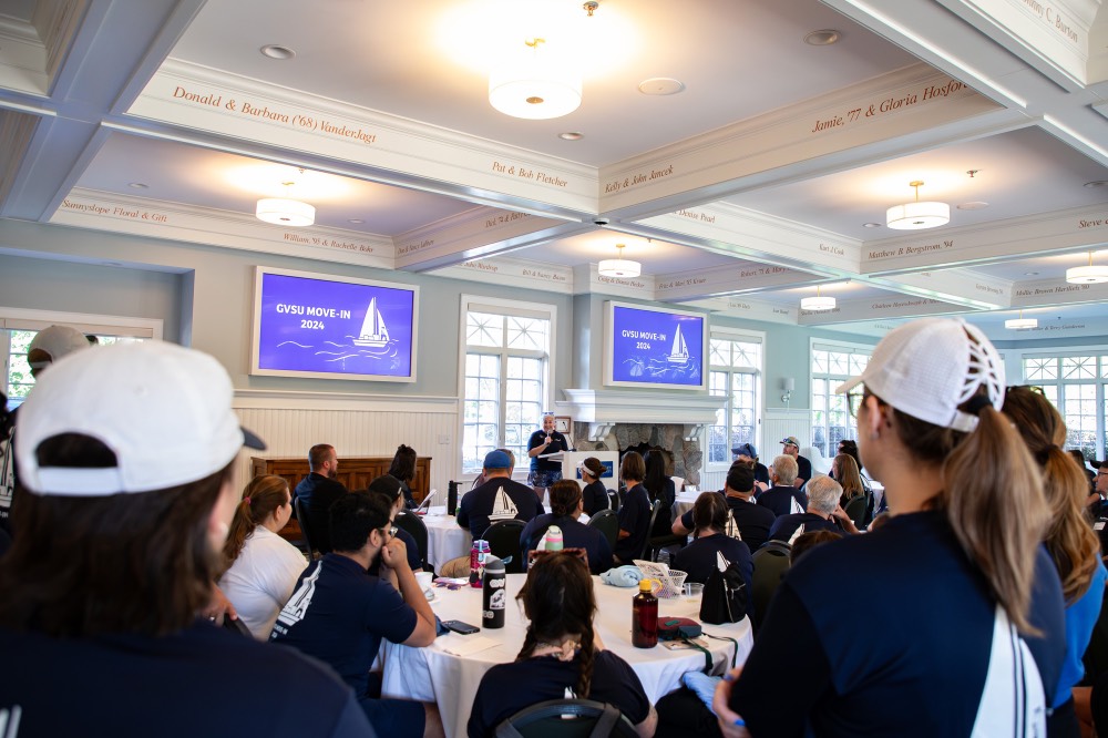 Large group of people gathered in the Alumni House and Visitor Center to talk about move in day